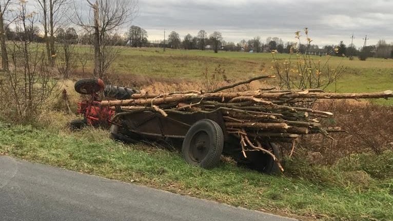 Ciągnik z furmanką drewna w rowie